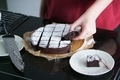 Close up hand taking piece of fresh homemade, sliced chocolate cake. - PhotoDune Item for Sale