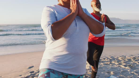 Senior african american couple practising yoga at the beach