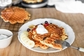 Stacked waffles in a white plate with sugar syrup, berries and banana slices ready to eat. - PhotoDune Item for Sale
