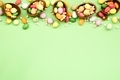 Easter flat lay with colourful candy sprinkles chocolate eggs on pastel green background. - PhotoDune Item for Sale