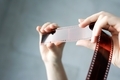 Analog photography on filmstrip . Hands holding photo negatives against the light. Retro style - PhotoDune Item for Sale