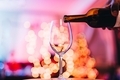 man pouring into wine glass against colorful bokeh lights background - PhotoDune Item for Sale