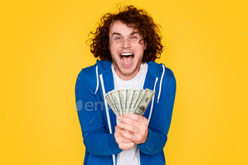 oking at camera while showing lottery prize money against bright yellow background