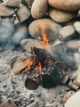 Burning wood in a smoky campfire made of rocks to protect it from the wind  - PhotoDune Item for Sale