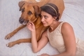 Beautiful young girl with her pet dog relaxing on the bed - PhotoDune Item for Sale