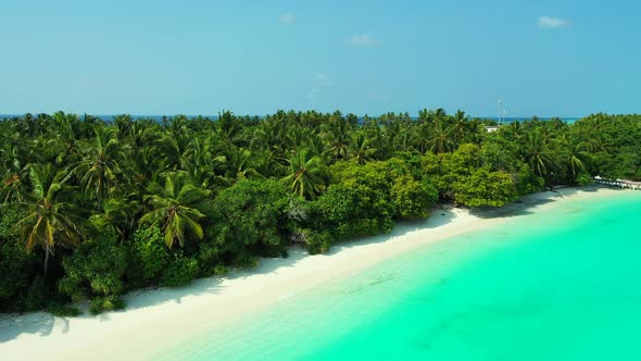 Wide flying tourism shot of a sunshine white sandy paradise beach and turquoise sea background in 4K