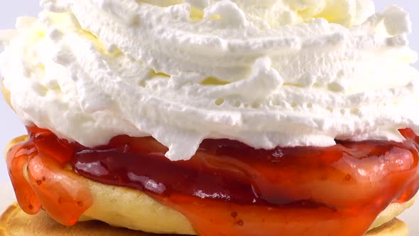 American pancakes with strawberry topping and whipped cream on a white background.