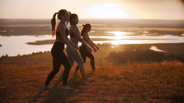 Three Young Women Doing Aerobic Exercises on Sunset - Doing Lunges