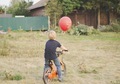 Bike biking kid orange red balloon countryside from behind  - PhotoDune Item for Sale