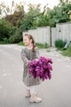 Cute little girl wearing dress holds a large bouquet of lilacs flowers. Spring concept - PhotoDune Item for Sale