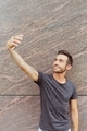 Portrait of young man standing outdoors while taking selfie - PhotoDune Item for Sale