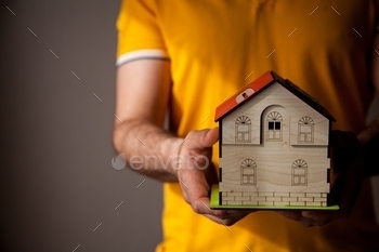 opy space on the left. Warm background of realtor holding a house. Real estate concept.
