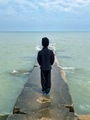 Young boy facing away all dressed in black on a pier looking at Lake Michigan  - PhotoDune Item for Sale