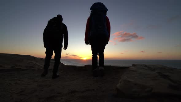 Hikers With Backpack Watching Sunset From Beach