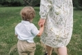 Pretty little boy holding his mother while walking in the park. View from behind. - PhotoDune Item for Sale