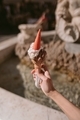 Woman holding a delicious ice cream cone against the background of a blurred fountain. - PhotoDune Item for Sale