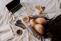 Young woman legs on bed with a dog using laptop with a cup of coffee  - PhotoDune Item for Sale
