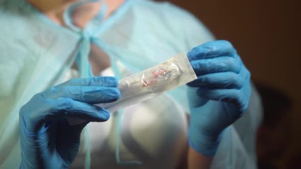 The Nurse Unfolds the Syringe and Needle