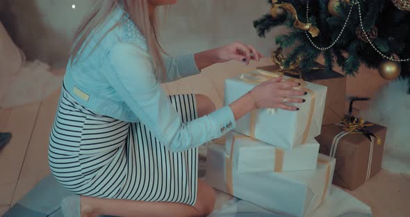 Girl Puts Under the Christmas Tree Boxes with Christmas Gifts