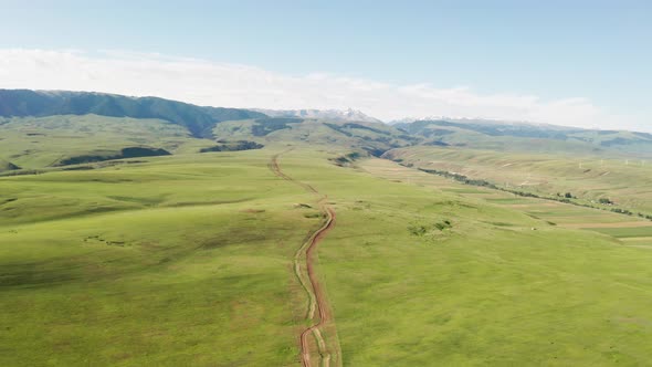 Mountain peaks and grassland are under white clouds