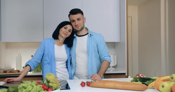 Smiling Married Couple in Love Standing on Kitchen Background and Posing on Camera