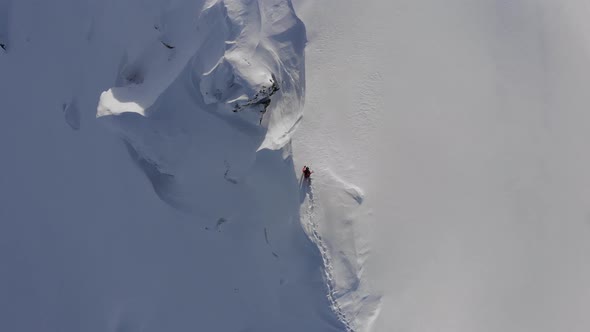 Drone shot of snowboarder walking on dangerous ridge in Austria