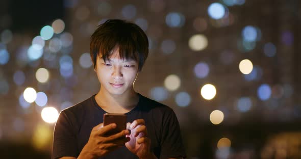 Man use of mobile phone in city at night