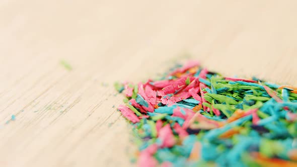 Various colored pencil shavings on wooden background