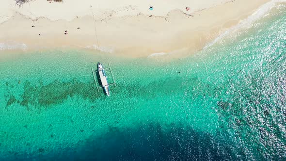 Jukung boat anchoring on tranquil shoreline of tropical island with white sandy beach washed by turq