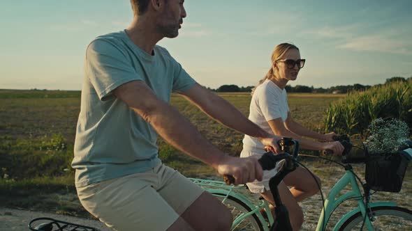 Cheerful caucasian couple of middle age riding a bike on sunset on village road. Shot with RED heliu