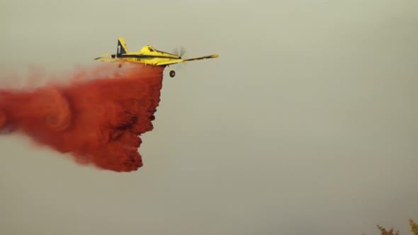 Fire fighter plane drops fire retardant on a forest fire in the hills