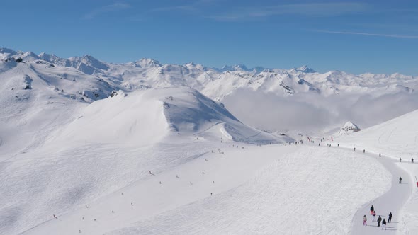 Many Skiers And Snowboarders Sliding Down Ski Slope In Snowy Mountains In Winter