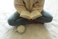 Midsection view of female seated on fur rug reading book with cocoa - PhotoDune Item for Sale