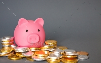 a pink toy Piggy Bank or money box surrounded by cash, coins, treasure, save, currency, gold, silver, financial, copy space, business, bank, banking, planning, future, fees, equity, cost, salary, wages.