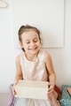 Seven year girl wearing beautiful dress holding birthday gift at home - PhotoDune Item for Sale