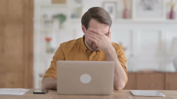 Young Man having Headache while Working on Laptop