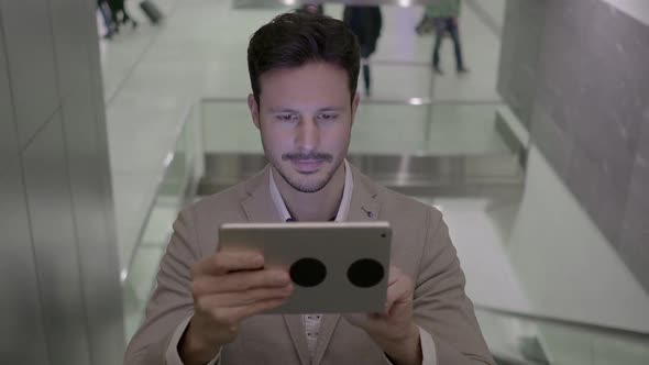 Lifestyle Portrait of Attractive Young Male Entrepreneur Browsing the Web Tablet Screen alt