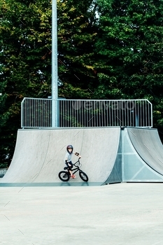 Boy in fullface helmet riding his bmx bike on radius in skate park