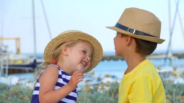 Adorable Little Boy and Girl in Straw Hats Are Laughing Together