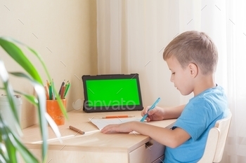 Smart school boy drawing picture, tablet with green screen stay on desk