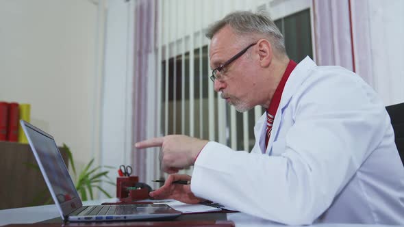 Happy doctor working on a laptop in modern clinic