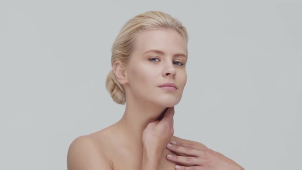 Studio portrait of young, beautiful and natural blond woman applying skin care cream. F