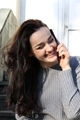 A young beautiful girl in a gray dress is talking on the phone and laughing - PhotoDune Item for Sale