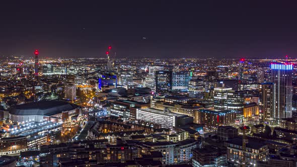 Aerial night time hyperlapse of Birmingham city centre with aircraft in the distance