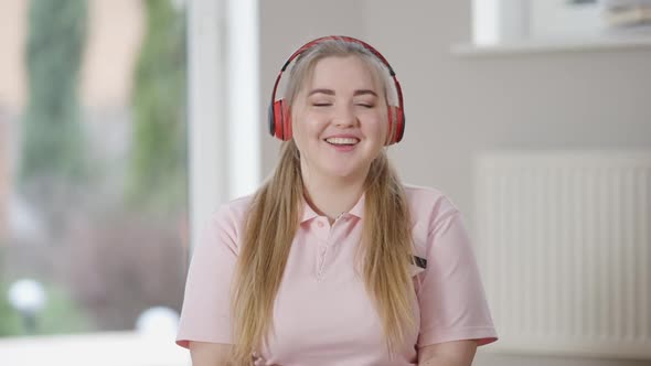 Charming Happy Young Plussize Woman Listening to Music in Headphones with Eyes Closed