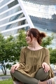 A young red-haired girl in a green chiffon blouse sits on the background of Moscow City - PhotoDune Item for Sale