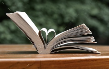 Photo of a book with pages folded like a heart on a table with green background