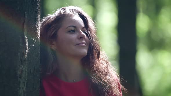 Joyful Brunette Woman is Resting in Forest at Sunny Weekend Looking at Nature