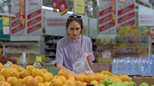 A Young Woman Buys Oranges in the Supermarket