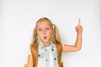 Smart school girl with backpack showing something interesting on white background